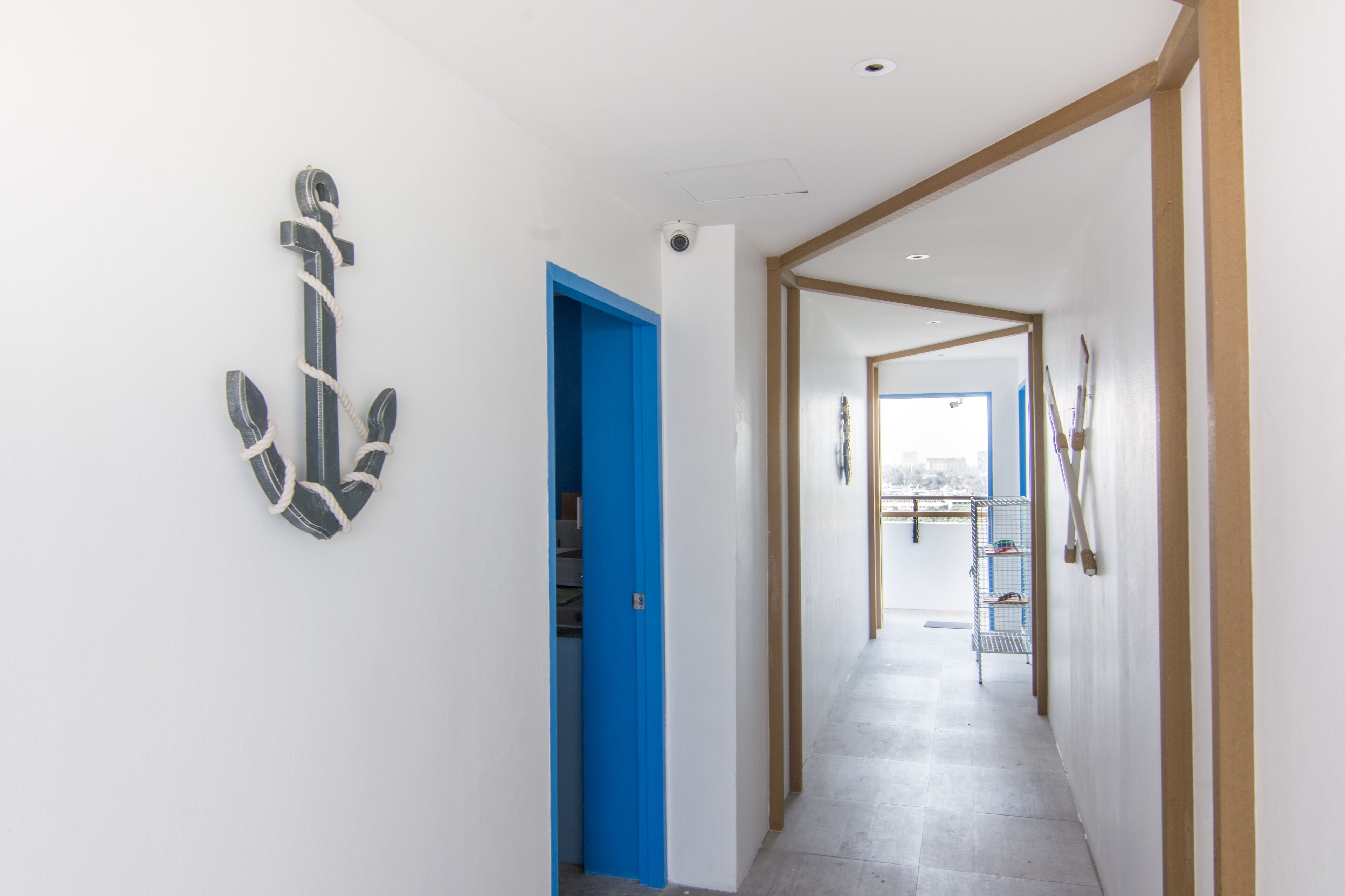 A hallway with a blue door, a metal rack, and a view through an open door.