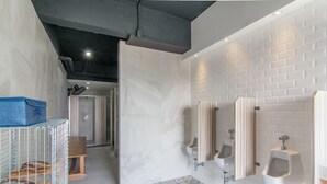 A modern bathroom with white subway tiles, a patterned floor, and multiple urinals.