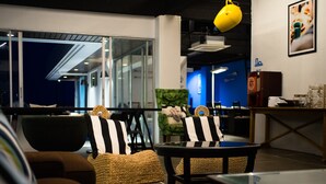A modern lounge area with wicker furniture, a glass table, and a view of the outside. - Thalay Cha Am Dorm Room of 6 Beds, A Co-living With Million Dollar View (Cha-am)