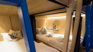 A bunk bed room with wooden headboards, a bedside table with a book, and a small shelf above the bed. - Thalay Cha Am Dorm Room of 6 Beds, A Co-living With Million Dollar View (Cha-am)