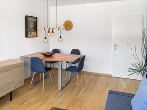 Ein Essbereich mit einem Holztisch, vier blauen Stühlen und einer hängenden Leuchte.