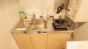 A compact kitchen with a sink, a dish rack, a coffee machine, and a toilet visible in the background. - Swwitch House Central Tokyo 7 (Tokyo)