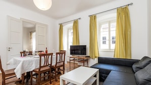 A living room with a sofa, a dining table with chairs, a TV, and yellow curtains. - Cozy apartment in Volosko with WiFi (Volosko)