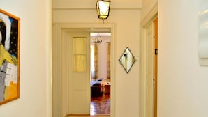 A hallway with a chandelier, a mirror, and a door leading to a room with a bed and a window. - Cozy apartment in Volosko with WiFi (Volosko)