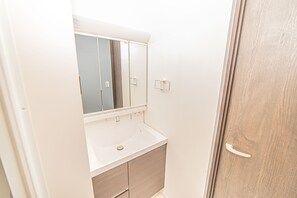 Uma casa de banho com uma pia branca, um espelho e uma porta de madeira.