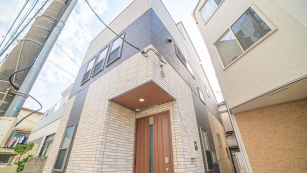 A corner building with a wooden door and a visible security camera. - Sumida family hotel in Tokyo (Tokyo)