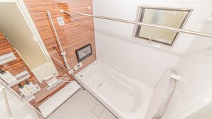 A modern bathroom with a wooden vanity, a bathtub, a window, and a shower area. - Sumida family hotel in Tokyo (Tokyo)