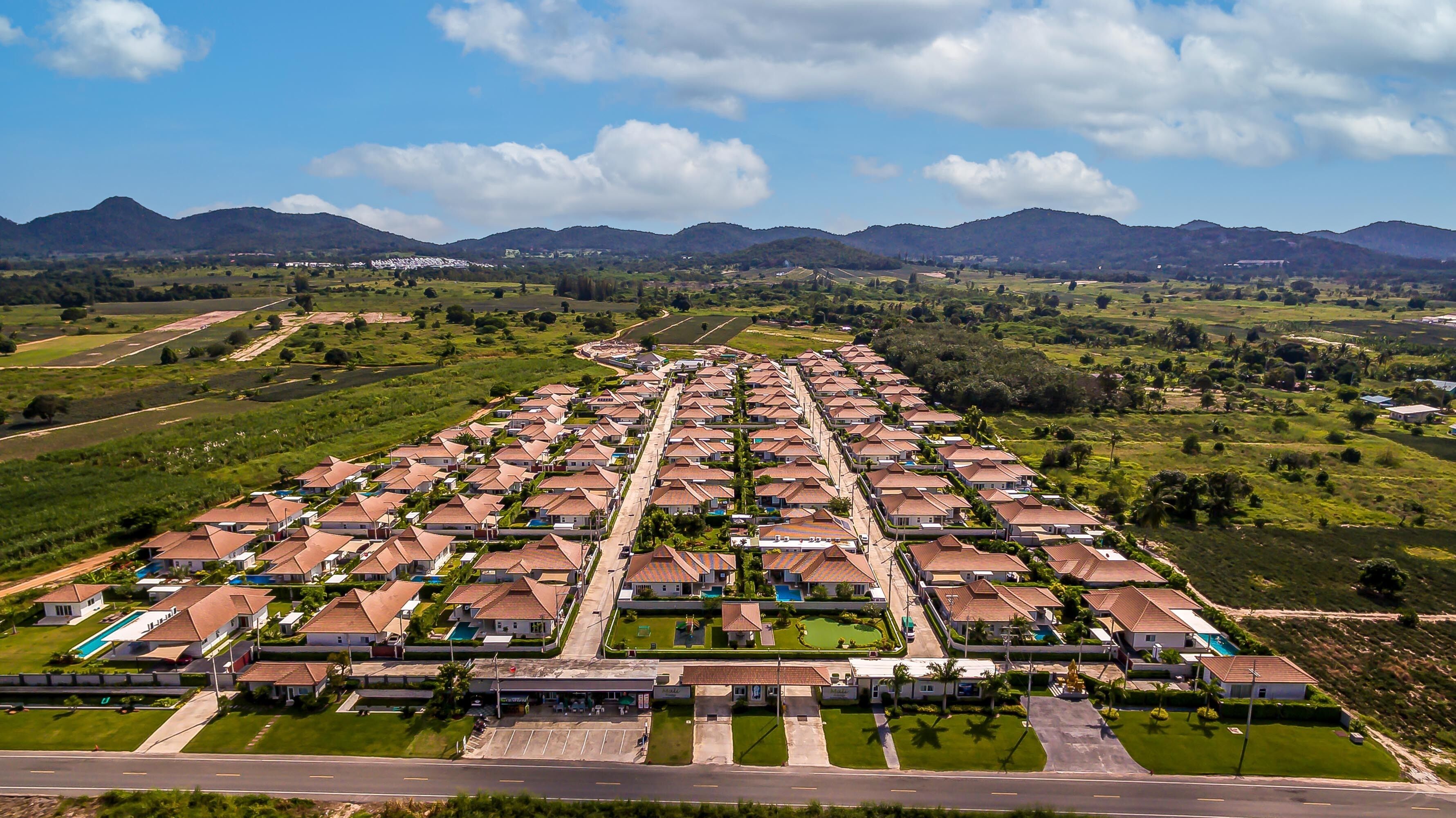 Un quartier résidentiel caractérisé par des maisons de style uniforme, une rue principale et de nombreux espaces verts environnants.