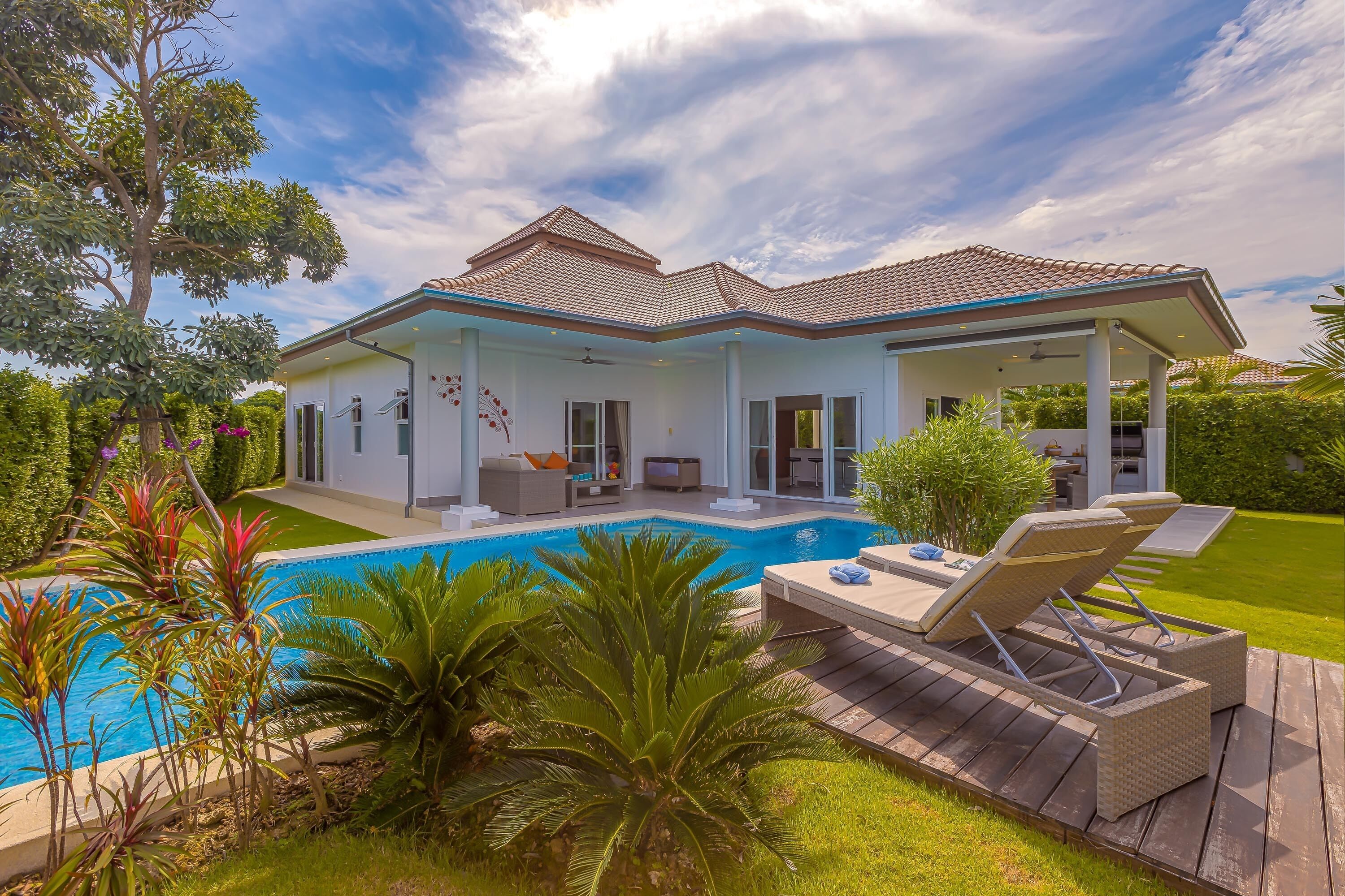 A modern house with a swimming pool, outdoor furniture, and a well-maintained garden.