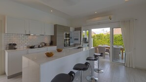 Una cucina moderna con isola centrale, sgabelli da bar e vista sull'esterno.