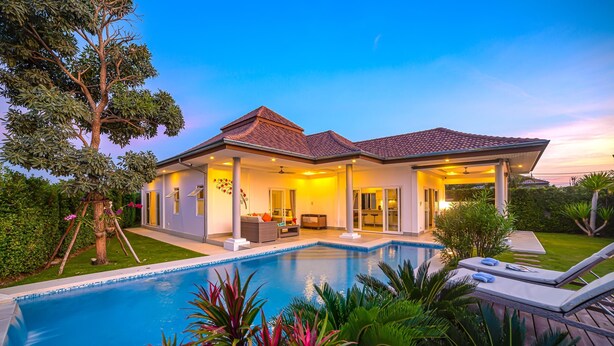 Una casa moderna con piscina, patio coperto e giardino curato.