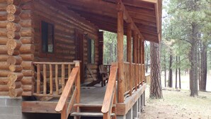 A log cabin with a wooden porch and steps leading to a deck. - Circle Pine Ranch-"The Real Log Cabin Experience" (Alpine)