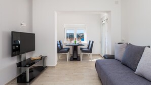 Un soggiorno moderno con una TV a schermo piatto, un divano e una zona pranzo con sedie e tavolo.