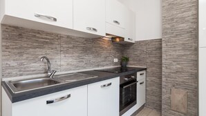 Una cucina moderna con mobili bianchi, un piano di lavoro nero, un lavello in acciaio inossidabile e un forno integrato.