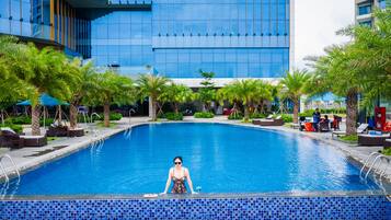 Una piscina al aire libre, sillones reclinables de piscina