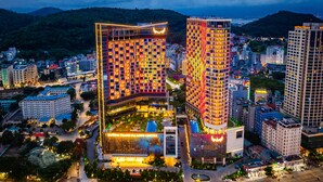A high-rise hotel with multiple floors, a rooftop pool, and a well-lit facade.