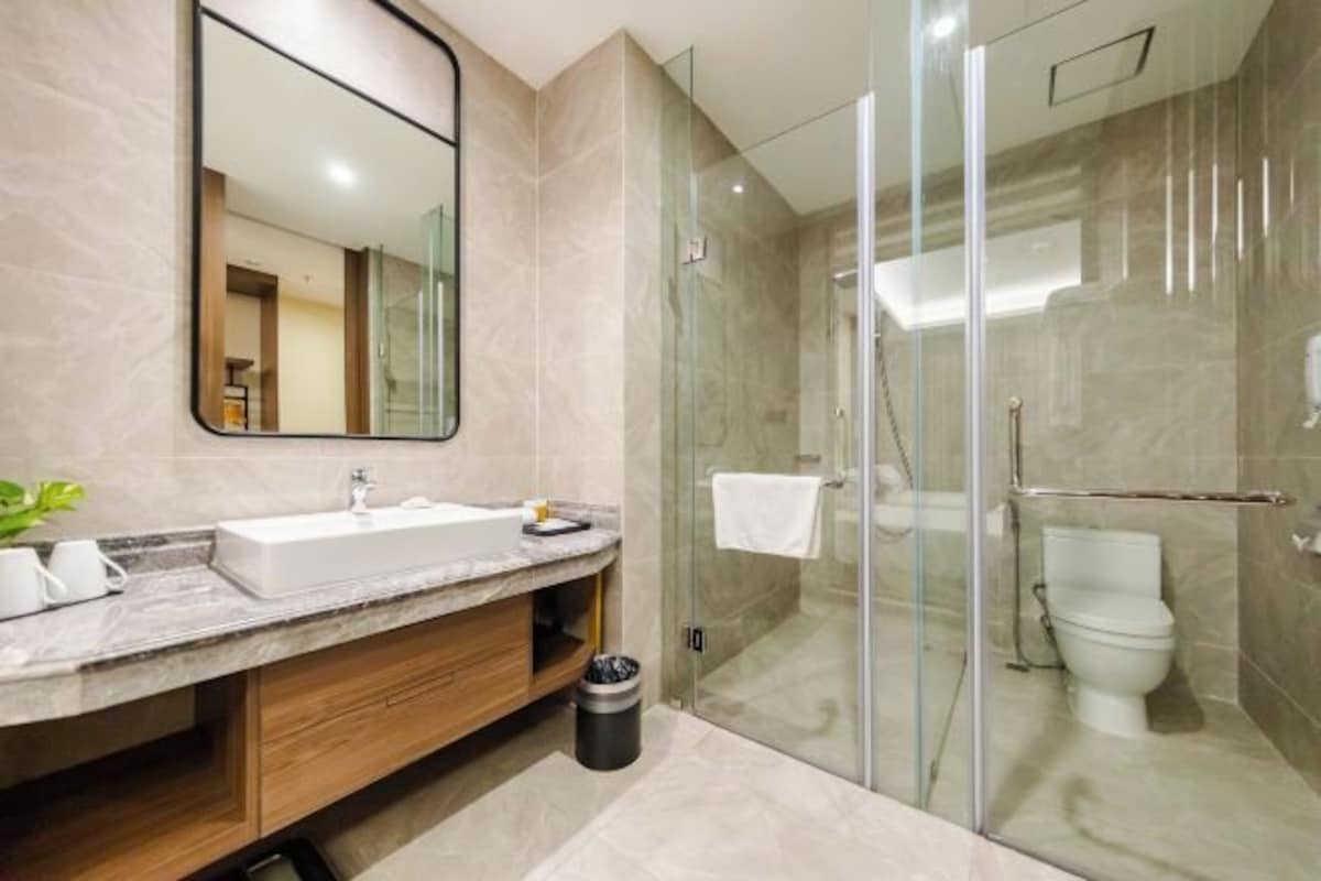 A modern bathroom with a glass-enclosed shower, a marble sink, and a large mirror.