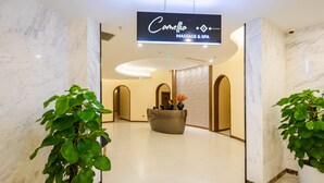 A reception area with a marble floor, a reception desk, and two potted plants.