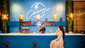 A bar area with a neon sign, bar stools, and a counter with a bartender.