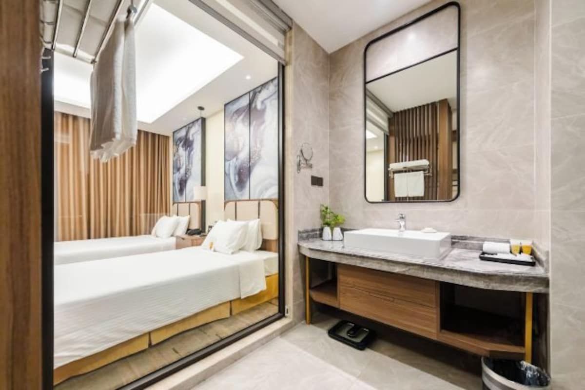A modern hotel room with a large bed, a separate bathroom with a vanity, and a large mirror.