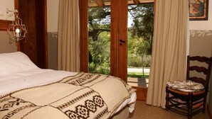 A bedroom with a bed, a chair, a door, a window with curtains, and a picture on the wall. - Alhue - Casa en el Golf (San Carlos de Bariloche)