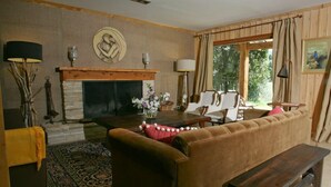 A cozy living room with a fireplace, a sofa, a coffee table, and a bench. - Alhue - Casa en el Golf (San Carlos de Bariloche)
