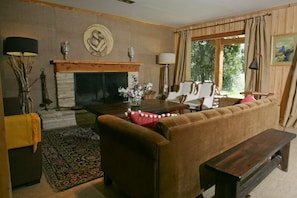 Un salon chaleureux avec une cheminée, un canapé, une table basse et un banc.