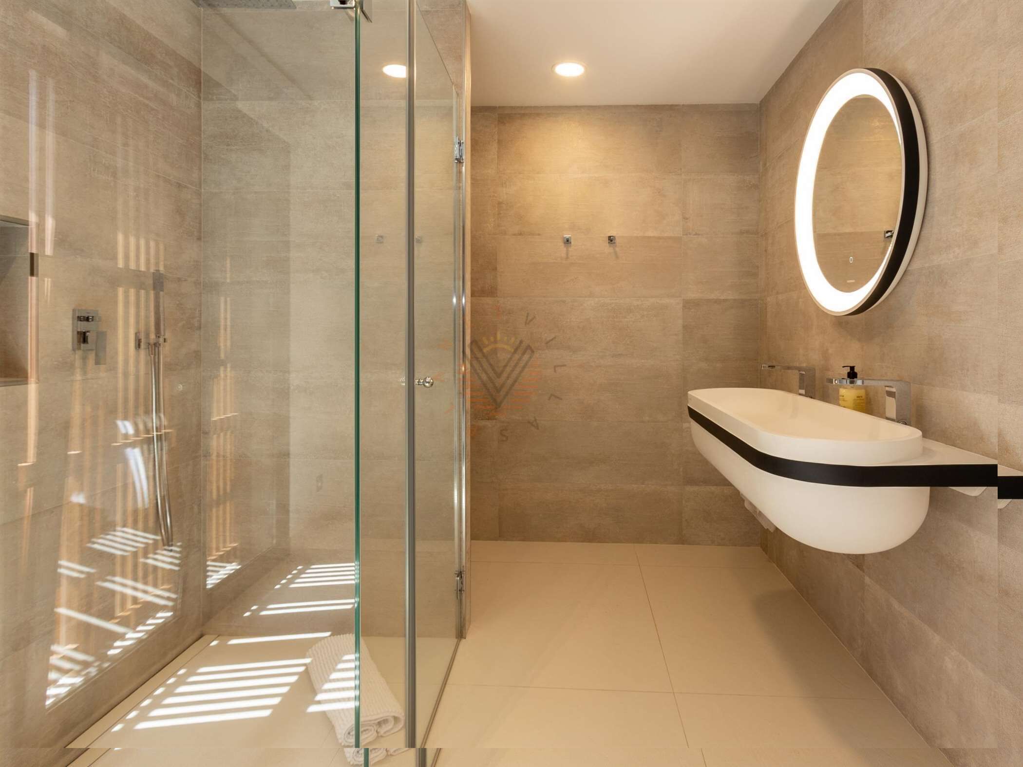 A modern bathroom with a glass-enclosed shower, a curved sink, and a wall-mounted mirror.