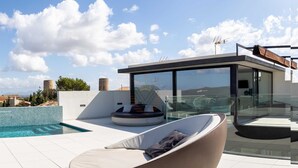 A modern rooftop pool area with a glass-enclosed lounge, a circular seating area, and a clear view of the surrounding landscape. - Montblau, luxury holiday villa (Buger)
