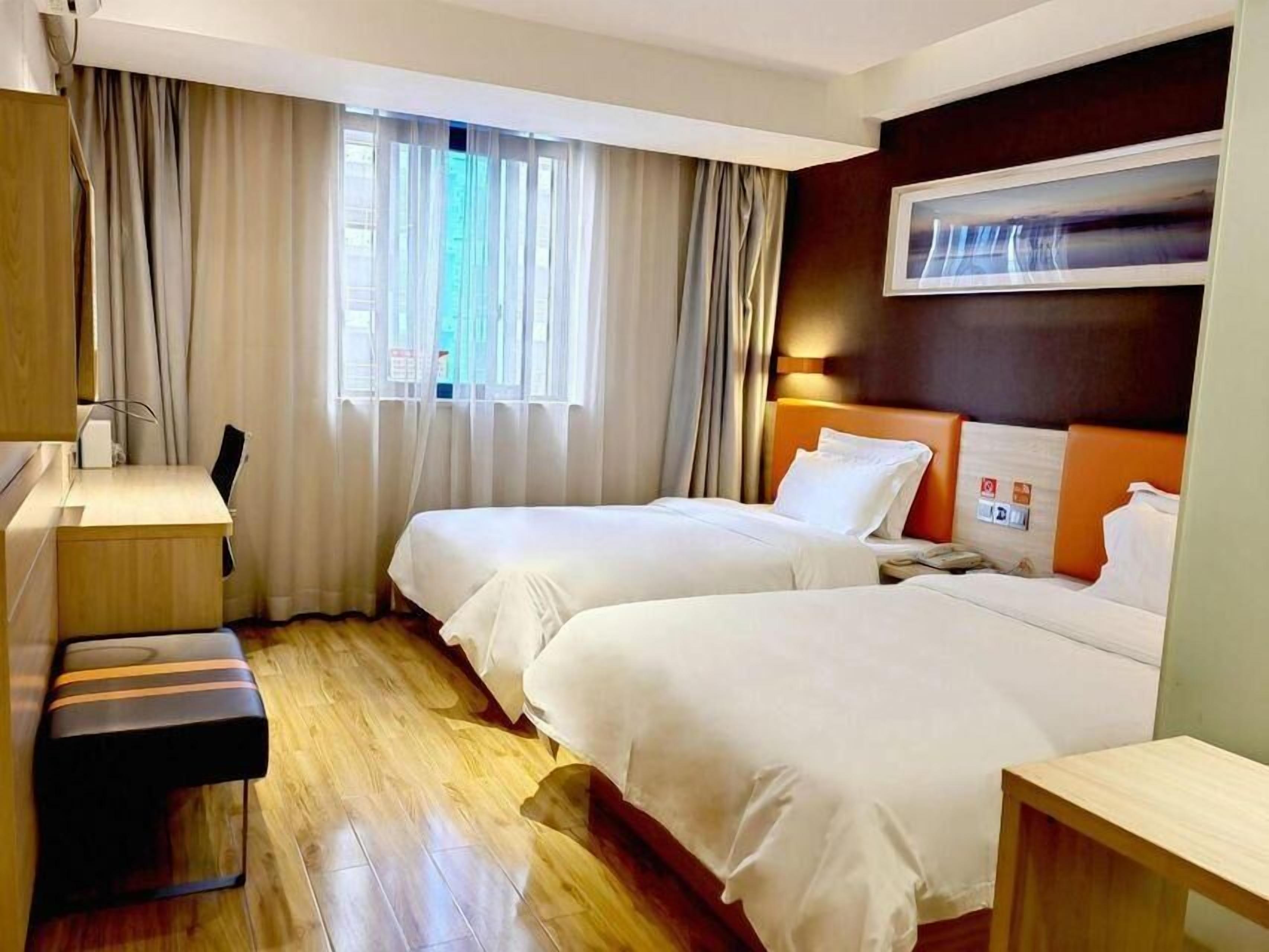 Ein Hotelzimmer mit zwei Betten, einem Schreibtisch und einem Stuhl.