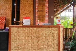 A reception area with a woven bamboo partition, a calendar, and a sign indicating the reception desk.
