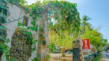 Un quartier résidentiel avec un bâtiment blanc recouvert de lianes vertes, un mur de pierre et une enseigne indiquant « OYO Banyu Asam Residence ».