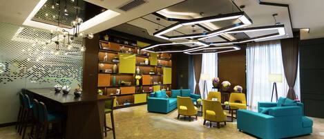 A modern lounge area with a bar, seating, and a bookshelf.