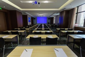 A conference room with rows of tables and chairs, a large screen at the front, and a projector. - Hampton by Hilton Lanzhou Mogao Avenue (Lanzhou)