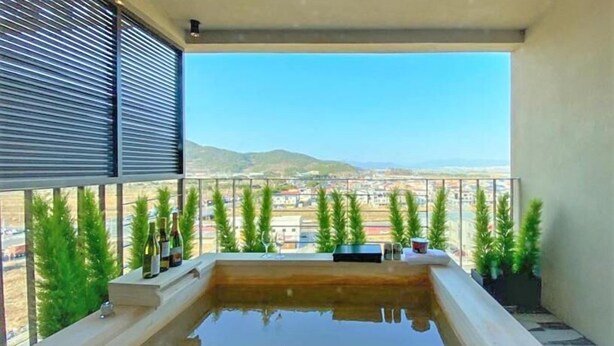 A balcony with a hot tub, potted plants, and a clear view of the cityscape. - Best Louis Hamilton Hotel West Busan (Busan)