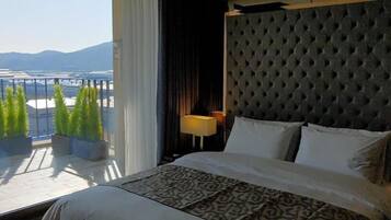 A hotel room with a large bed, a view of mountains, and potted plants.