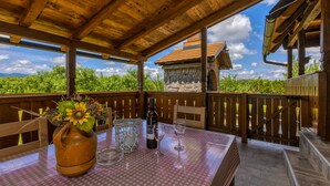 Una terraza de madera con una mesa dispuesta para dos, con vistas a un viñedo.