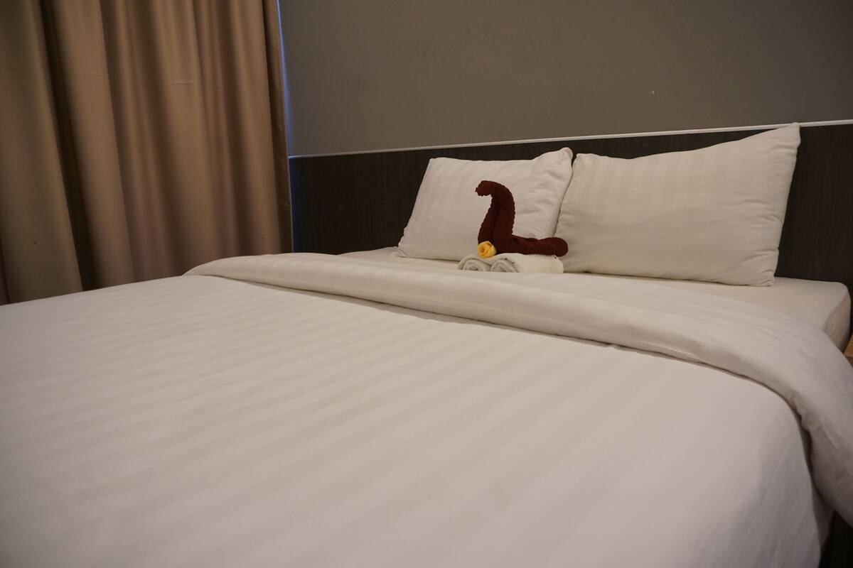 A hotel room with a neatly made bed, a headboard, and a curtain.