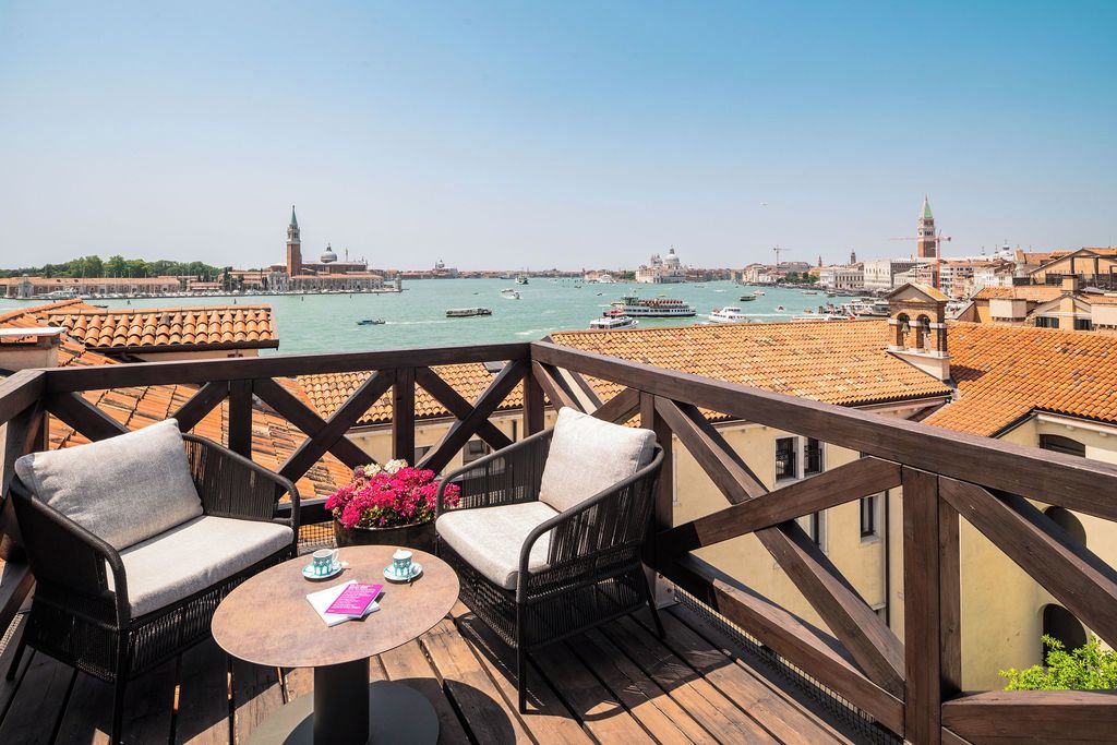 Ein Balkon mit Korbmöbeln und Blick auf den Canal Grande in Venedig.