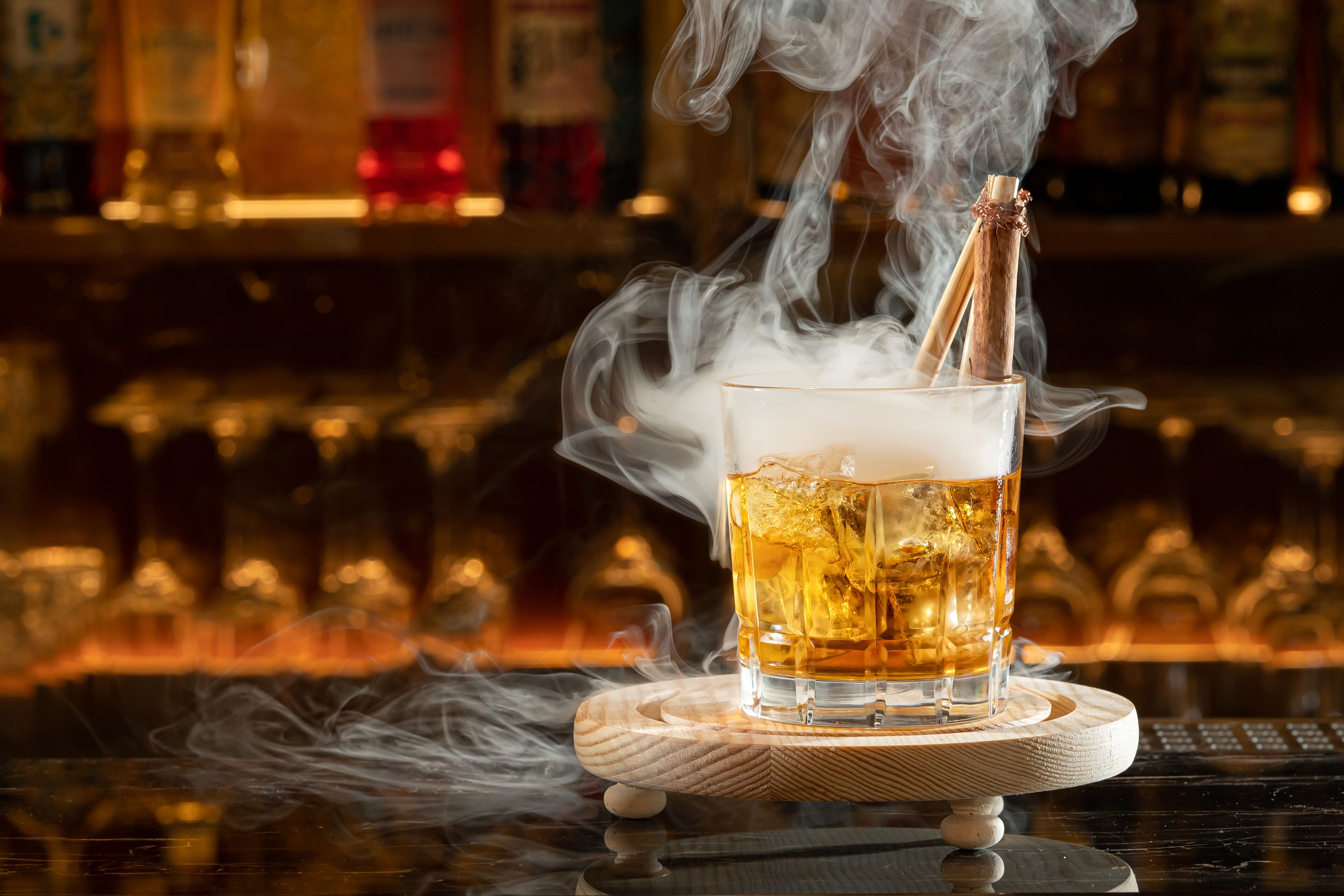 A glass of beer with a smoking device on a coaster, with a bar in the background.