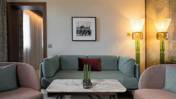 A modern living room with a green sofa, a marble coffee table, and a cactus plant.