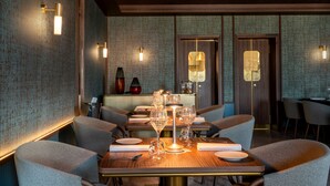 A dining area with a wooden table set for a meal, surrounded by upholstered chairs. - Ca' di Dio - VRetreats, SLH Collection (Venice)