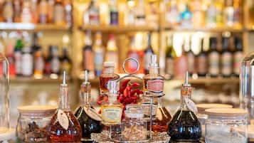 A variety of bottles and containers on a bar counter, including a bottle labeled "Bordiga 1906 Limone" and a jar with dried flowers.