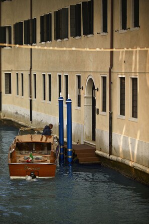 A boat named 'Unica' docked at a canal with a building in the background.
