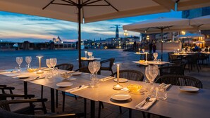 An outdoor dining area with tables set for two, featuring a view of the city skyline at dusk. - Ca' di Dio - VRetreats, SLH Collection (Venice)