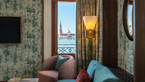 A room with a view of a historic building, a sofa, a chair, a lamp, and a small table with a book and glasses. - Ca' di Dio - VRetreats, SLH Collection (Venice)