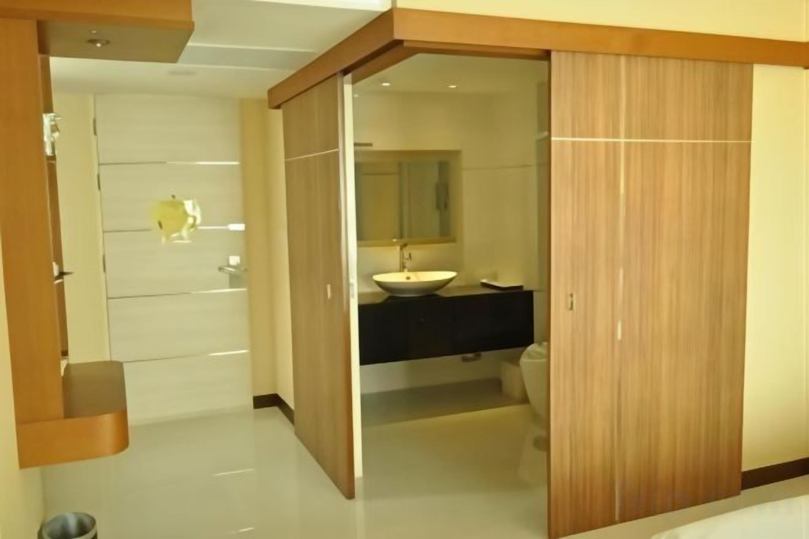 A modern bathroom with a wooden vanity, a sink, and a mirror.