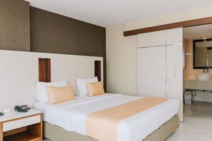 Ein Hotelzimmer mit einem großen Bett, einem Nachttisch mit Telefon und einem Kleiderschrank.