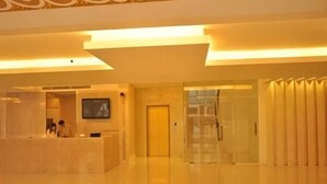 Una zona de recepción con mostrador, televisor y una puerta que da a otra habitación.