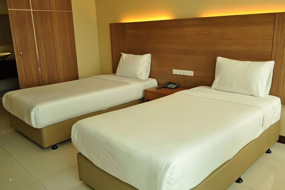 Two single beds with wooden headboards, a bedside table with a phone, and a wardrobe.